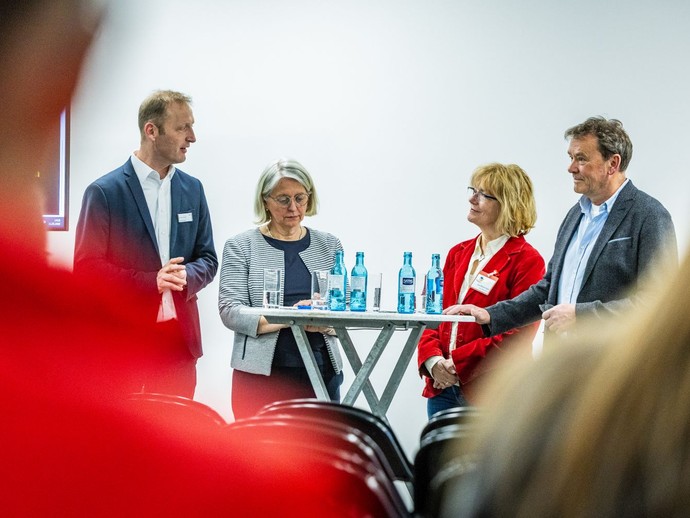 Vier Personen stehen an einem Stehtisch im Seminarraum und diskutieren miteinander. (vergrößerte Bildansicht wird geöffnet)