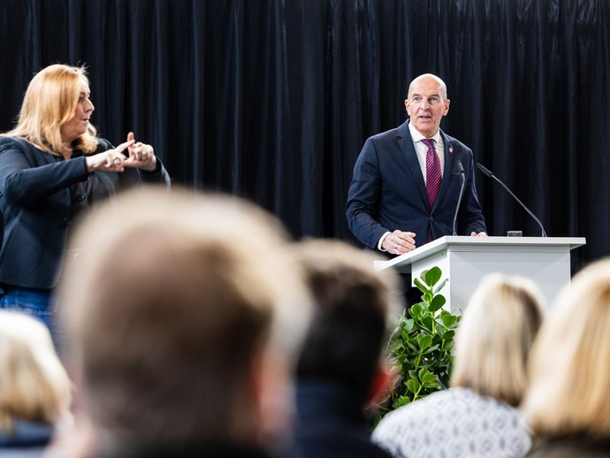 Dr. Georg Lunemann hält eine Rede, die von einer Gebärdendolmetscherin übersetzt wird. (vergrößerte Bildansicht wird geöffnet)