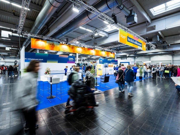 Viele Besucherinnen und Besucher stehen dicht gedrängt am Messestand und informieren sich über Inklusionsangebote im Arbeitsleben. (vergrößerte Bildansicht wird geöffnet)
