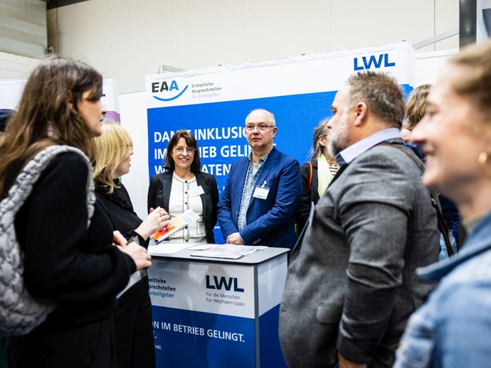 Mehrere Personen stehen an einem Messestand und führen Gespräche. (vergrößerte Bildansicht wird geöffnet)