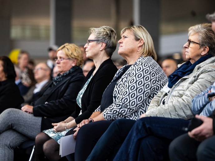 Besucherinnen und Besucher sitzen in Reihen und hören einem Redner auf der Bühne zu. (vergrößerte Bildansicht wird geöffnet)