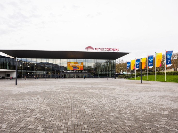 Die Messehalle in Dortmund ist von außen zu sehen, mit einem großen Banner am Eingang und Fahnen mit Messemotiven. (vergrößerte Bildansicht wird geöffnet)