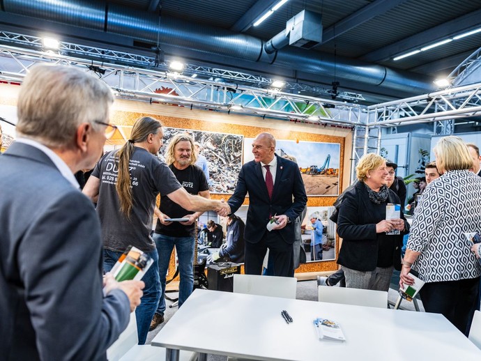 Dr. Georg Lunemann schüttelt einem Mann die Hand, während weitere Personen um sie herumstehen. (vergrößerte Bildansicht wird geöffnet)