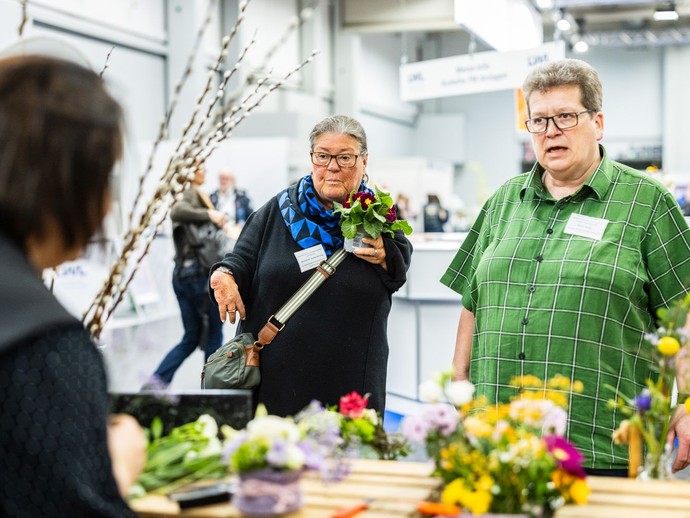 Zwei Besucher sprechen an einem Messestand mit einer weiteren Person. (vergrößerte Bildansicht wird geöffnet)